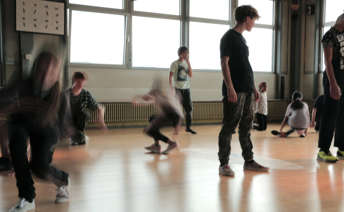 Kinder bewegen sich in einer lichtdurchfluteten Turnhalle