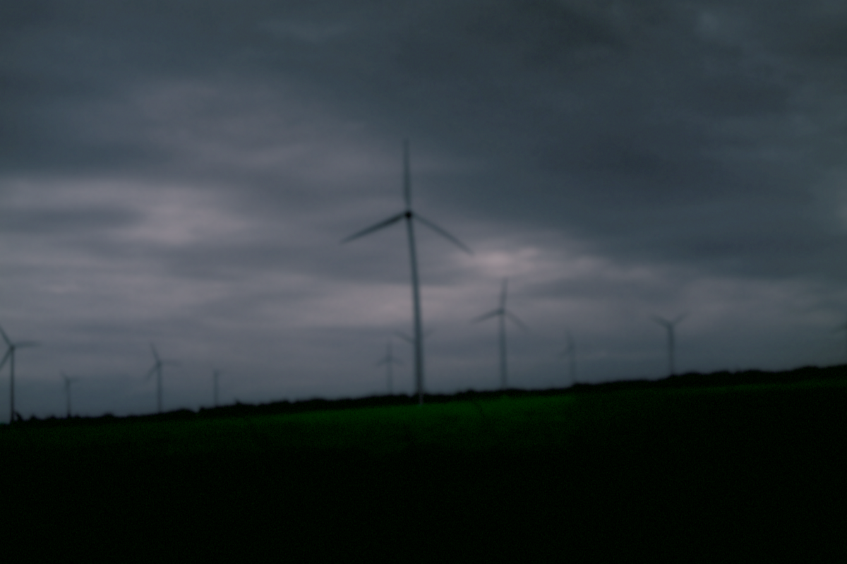 Windräder kurz vor Einbruch der Nacht unter dunklen leicht violetten Wolken