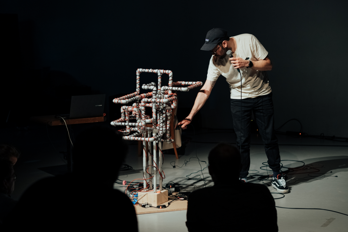 Sébastien Vaillancourt steht vor seiner Installation «overingengineered», die aus Plastikröhren besteht, die in Kabel eingewickelt sind, welche mit einem Laptop verbunden sind.