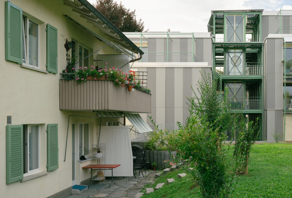 Sicht auf grünen Garten und Balkon mit Blumen einer Wohnung