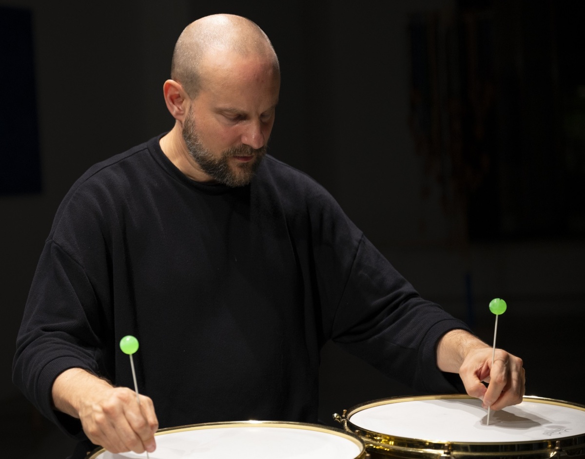 Foto von Etienne Nillesen, der an zwei Metallstäbe auf zwei Snare Drums hält