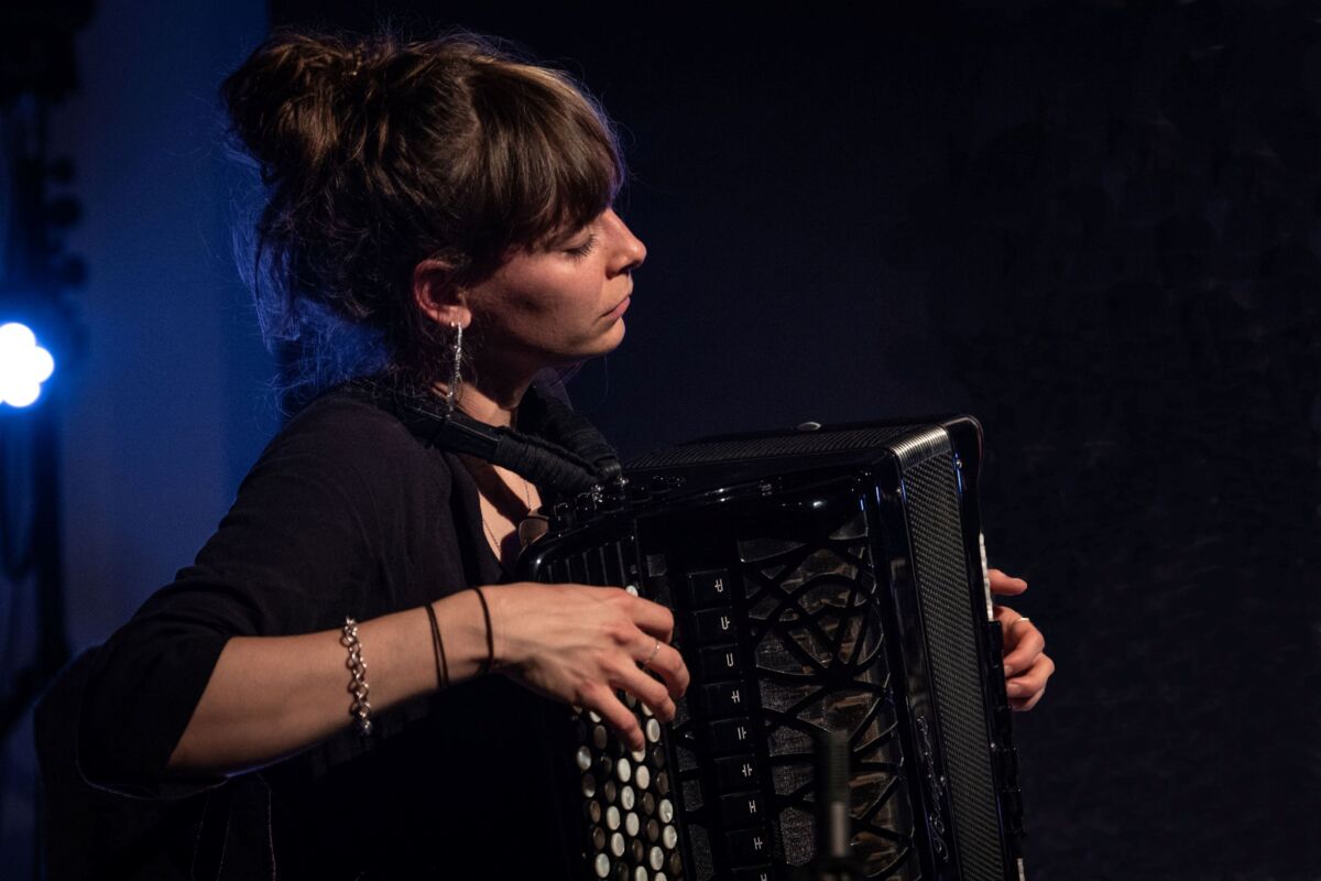 Das Foto zeigt Tizia Zimmermann, die gerade in das Akkordeon spielen versunken ist auf einer Bühne.